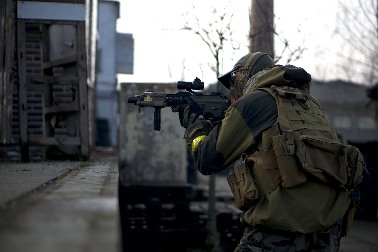 Services A soldier in camouflage with a rifle prepares in an urban environment, ready for action.