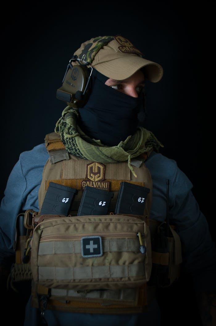 Home Portrait of a person in tactical gear and face covering in a studio setting.