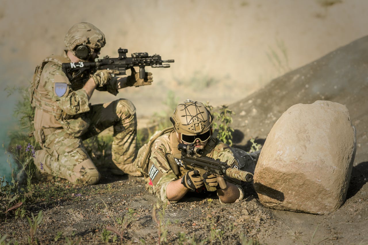 Services Two soldiers in camouflage uniforms practice tactical maneuvers in a desert environment, exhibiting teamwork and precision.